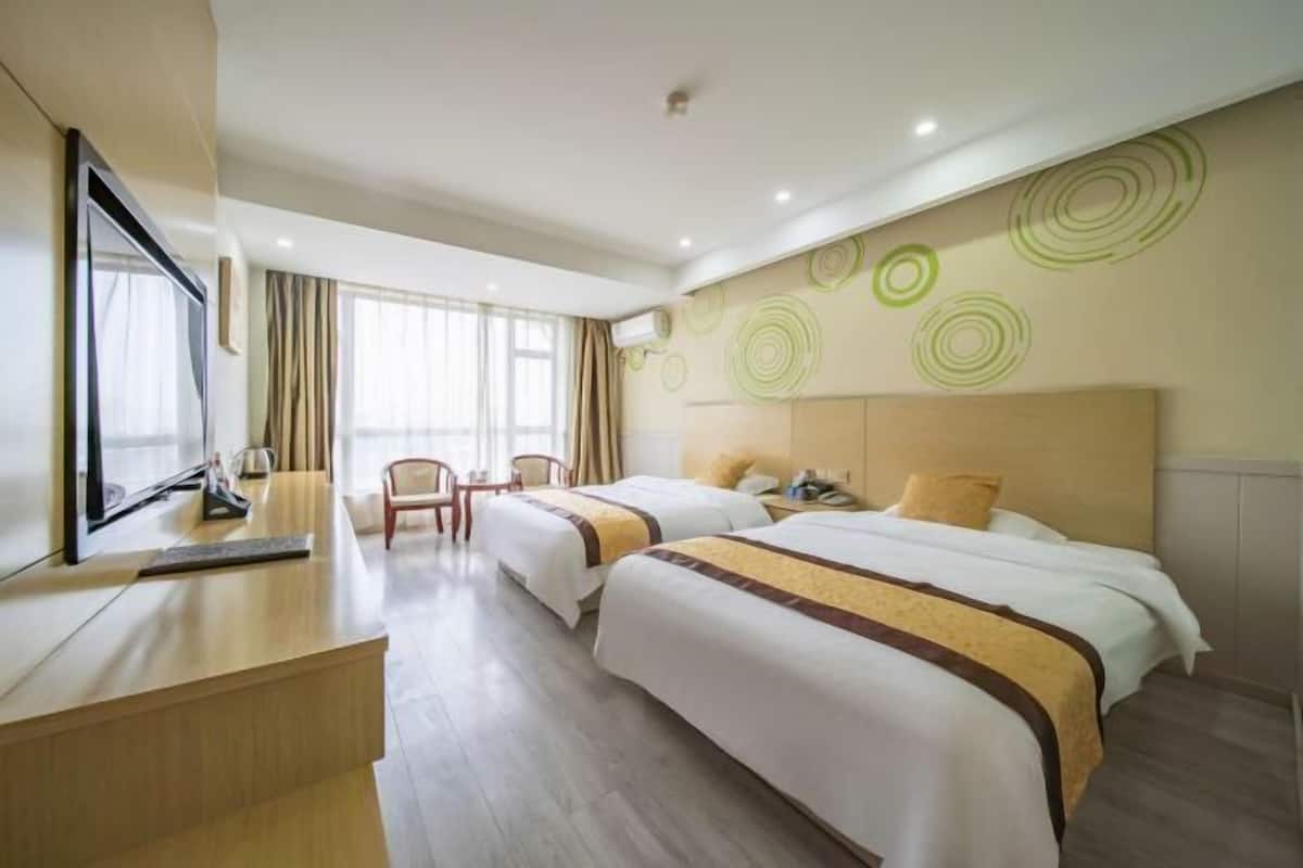 A hotel room with two beds, a desk, a chair, and a large mirror.