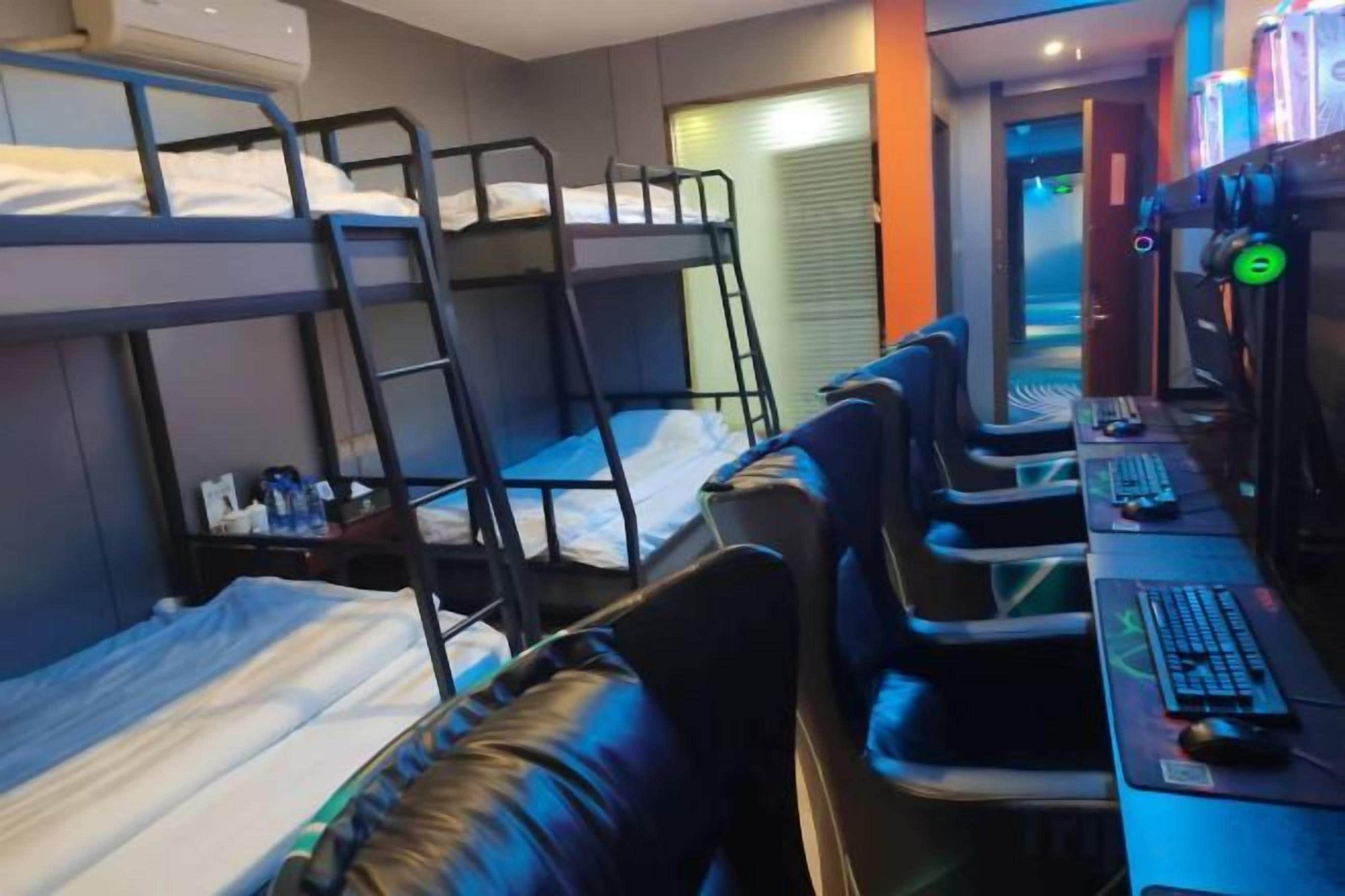 A bunk bed room with a desk and chair, a computer, and a window.