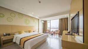 A hotel room with a large bed, a desk, a TV, and a view of the city. - The Wall Street Holiday Hotel (Yichun)