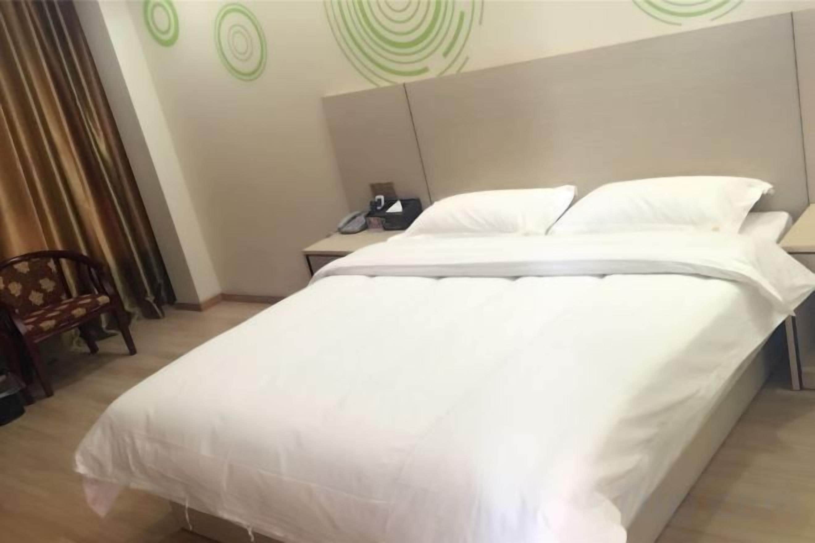 Une chambre d’hôtel avec un grand lit, une table de chevet, une chaise et un mur orné de motifs circulaires.