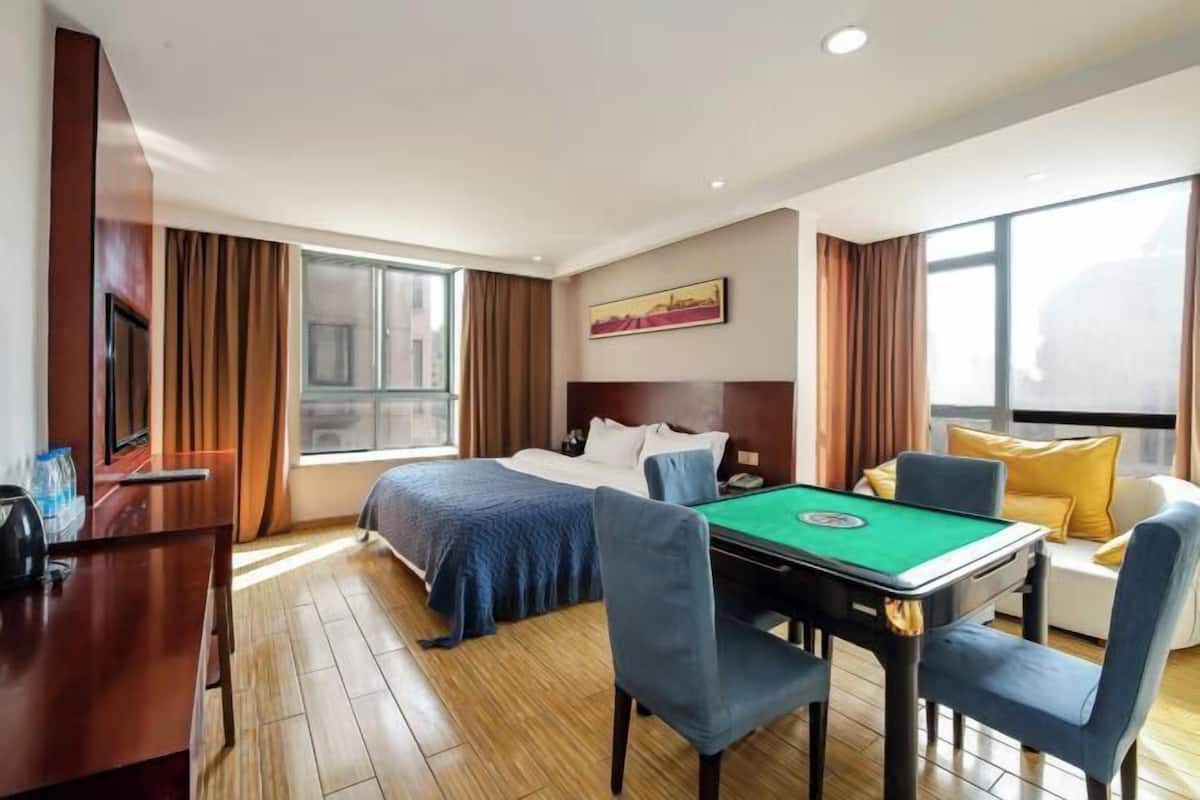 A hotel room with a bed, a desk with a telephone, a pool table, and a sofa with cushions.
