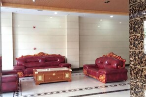 A lobby with two red leather sofas and a wooden coffee table. - The Wall Street Holiday Hotel (Yichun)