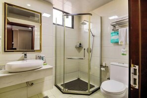 A bathroom with a glass-enclosed shower, a white sink, and a toilet. - The Wall Street Holiday Hotel (Yichun)