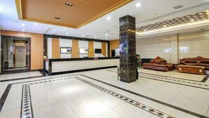 A hotel lobby with a reception desk, a large pillar, and a seating area with sofas. - The Wall Street Holiday Hotel (Yichun)