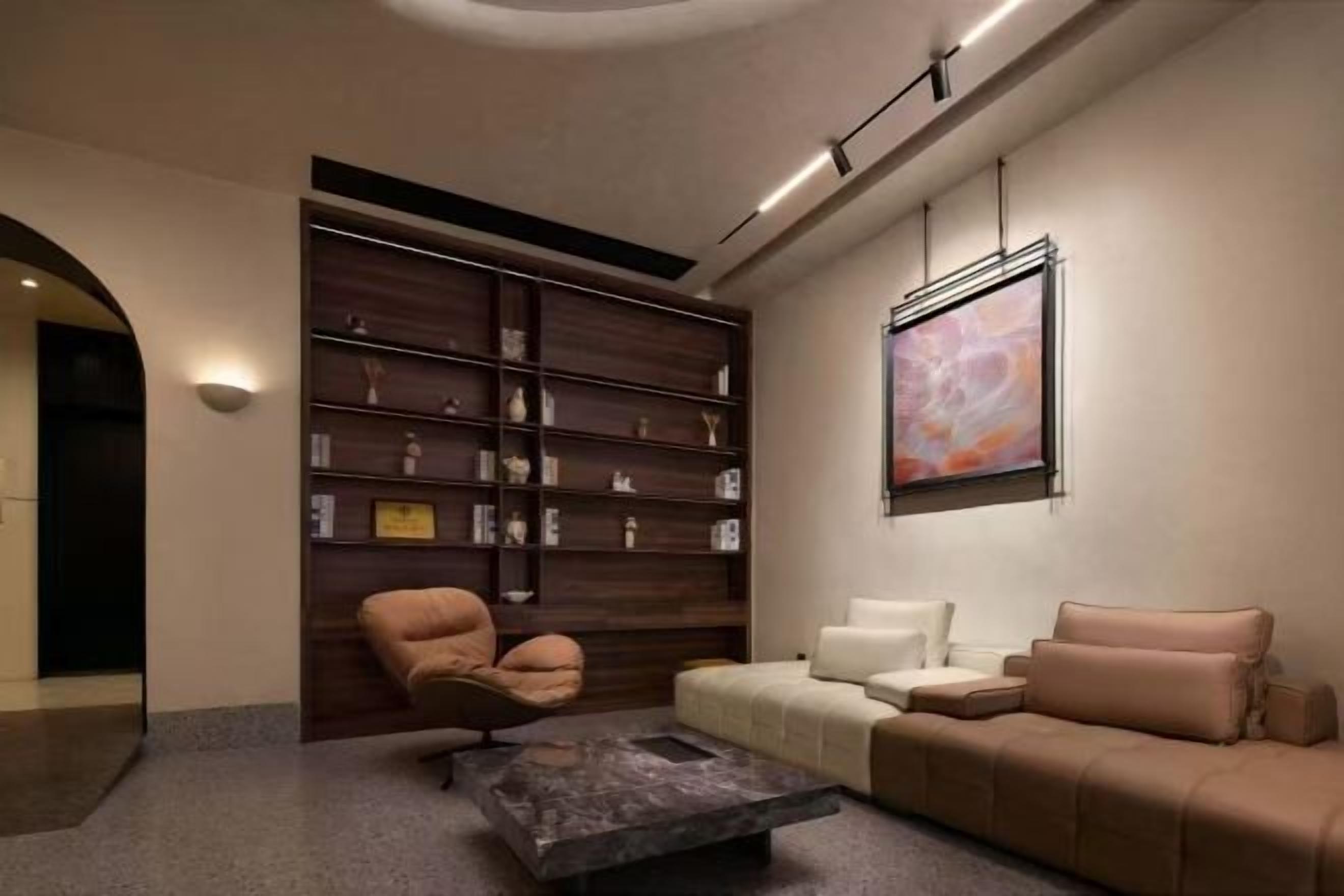 Um interior moderno com sofá, poltronas, mesa de centro e estante de livros.