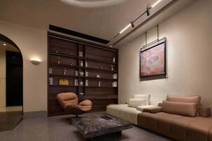 Un interior moderno con un sofá, sillones, una mesa de centro y una estantería.