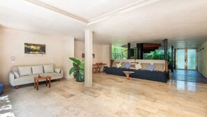 Uma sala de estar ampla com sofá, mesa de centro e um espaço de jantar com cadeiras.