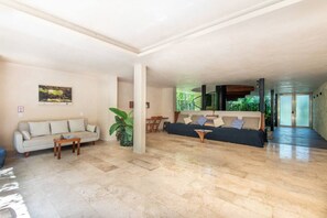 A spacious living area with a sofa, a coffee table, and a dining area with chairs. - Jungle Loft Suite - Santuario Hotel Boutique (Tulum)