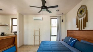 Quarto com cama, cabeceira de madeira, ventilador de teto, janela e ar-condicionado fixado na parede.