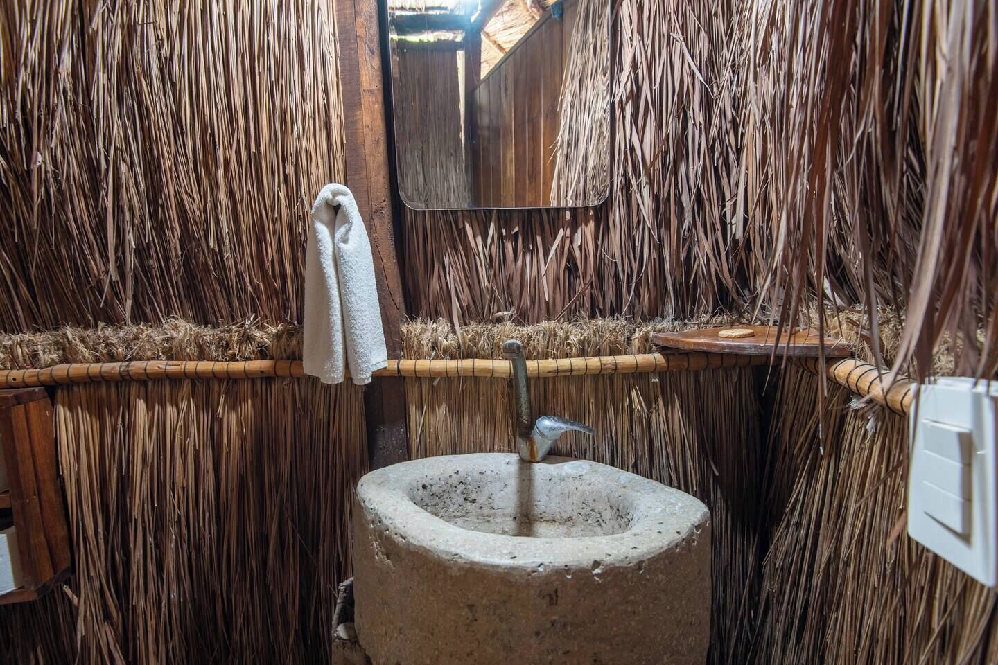 Ein rustikales Badezimmer mit einer Lehmwand, einem Betonsink und einem hängenden Handtuch.