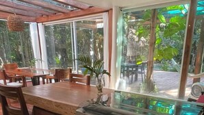 Une cuisine dotée d’un îlot central en bois, d’une cuisinière à gaz et de grandes fenêtres donnant sur un jardin.