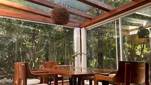 Un espace repas doté d’un plafond en verre, de meubles en bois et d’un luminaire suspendu.