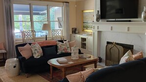 Een woonkamer met een bank, een bijzettafeltje, een open haard en een televisie.