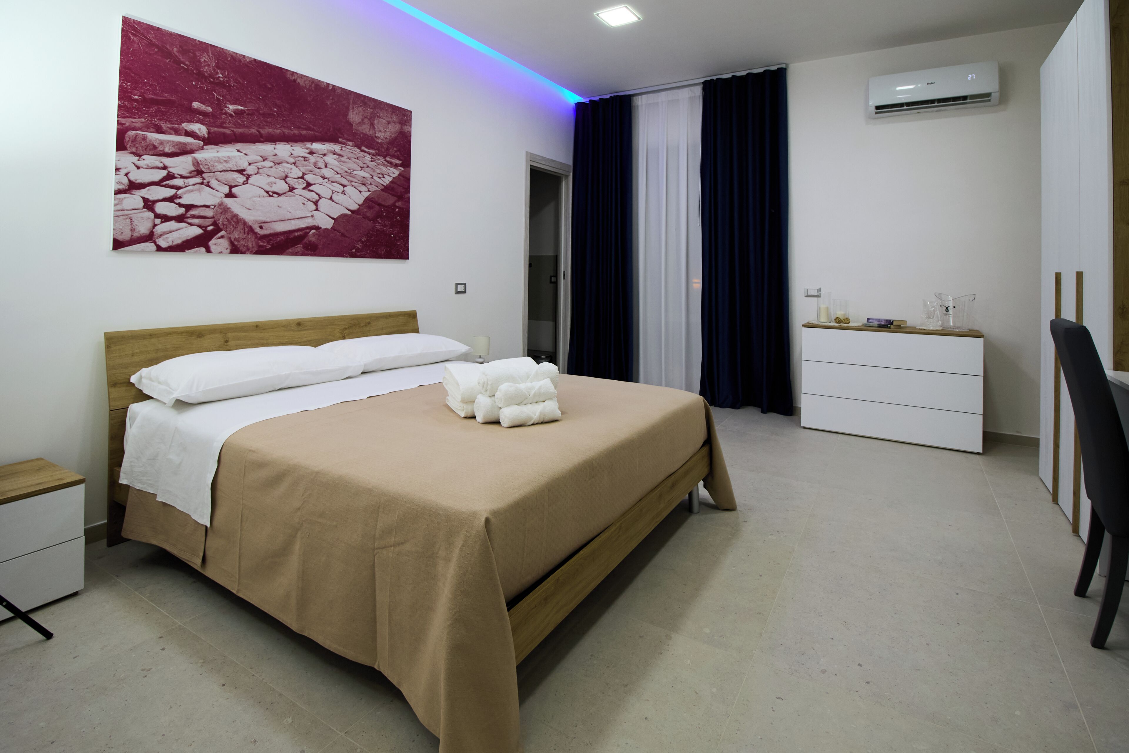 Un dormitorio ordenado con cama, mesita de noche y cómoda.