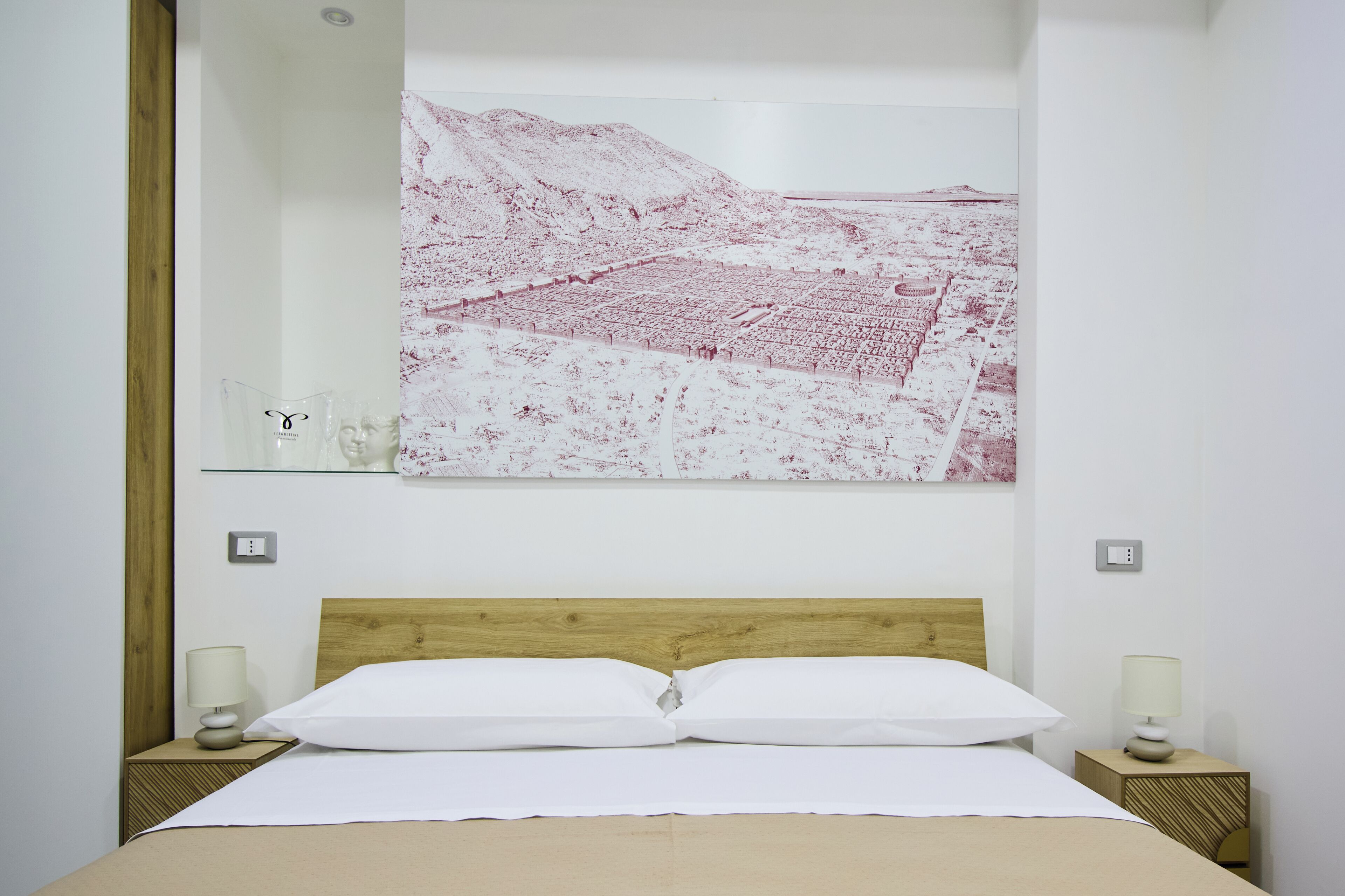 Une chambre d’hôtel comprenant un lit, deux tables de chevet, une œuvre d’art accrochée au mur et un miroir.