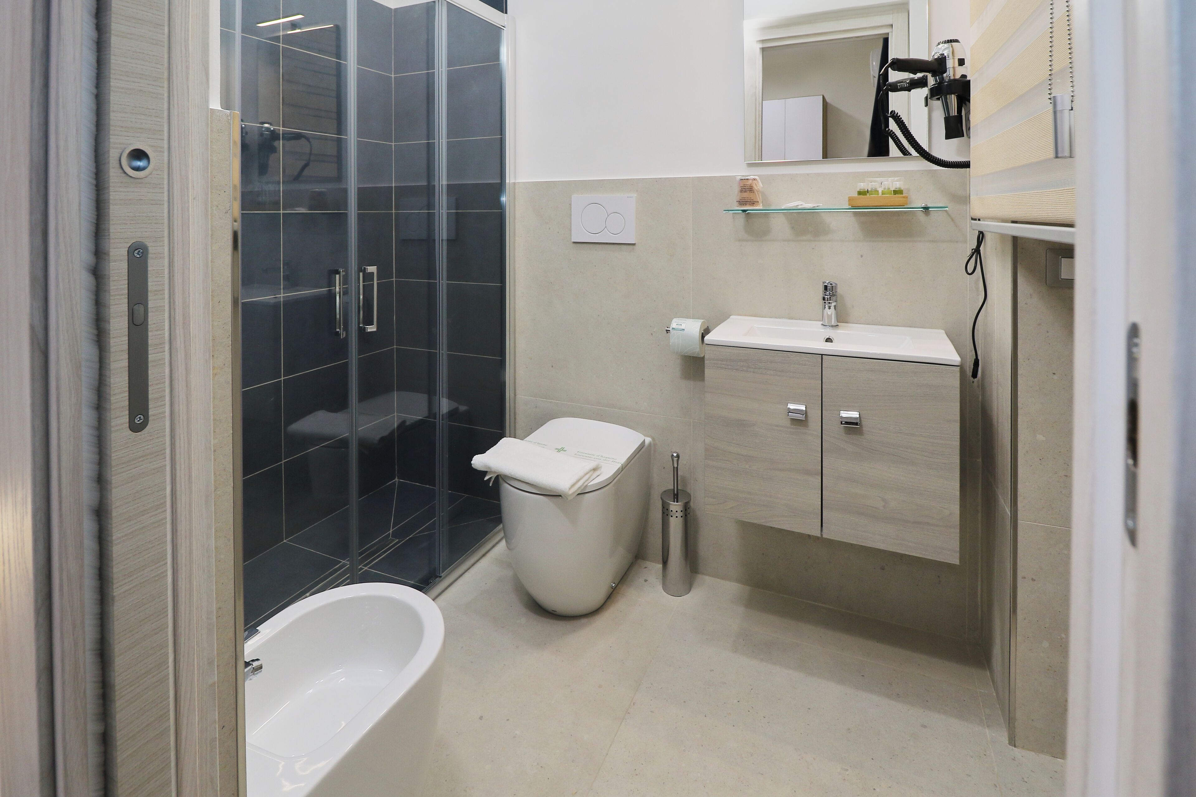 Un bagno moderno con cabina doccia in vetro, vasca da bagno bianca, lavabo con specchio sopra e un water.