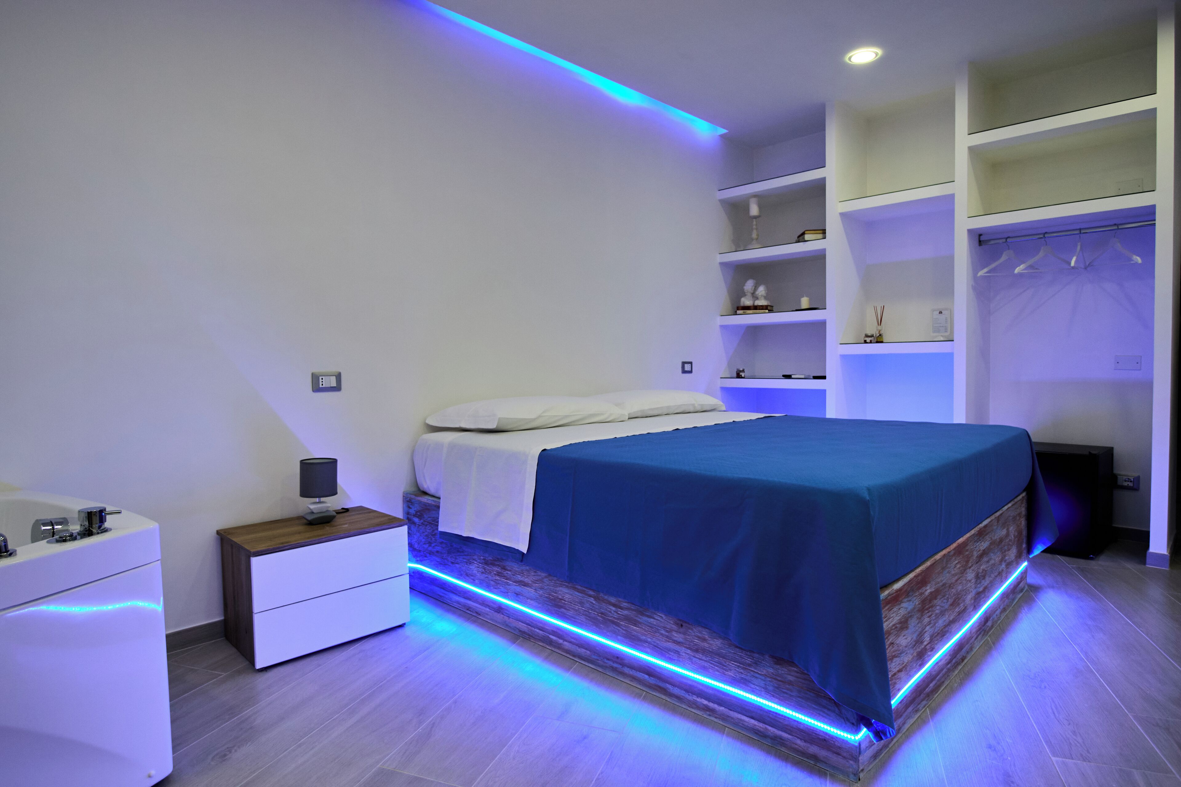 A modern bedroom with a bed, bedside tables, and built-in shelving.