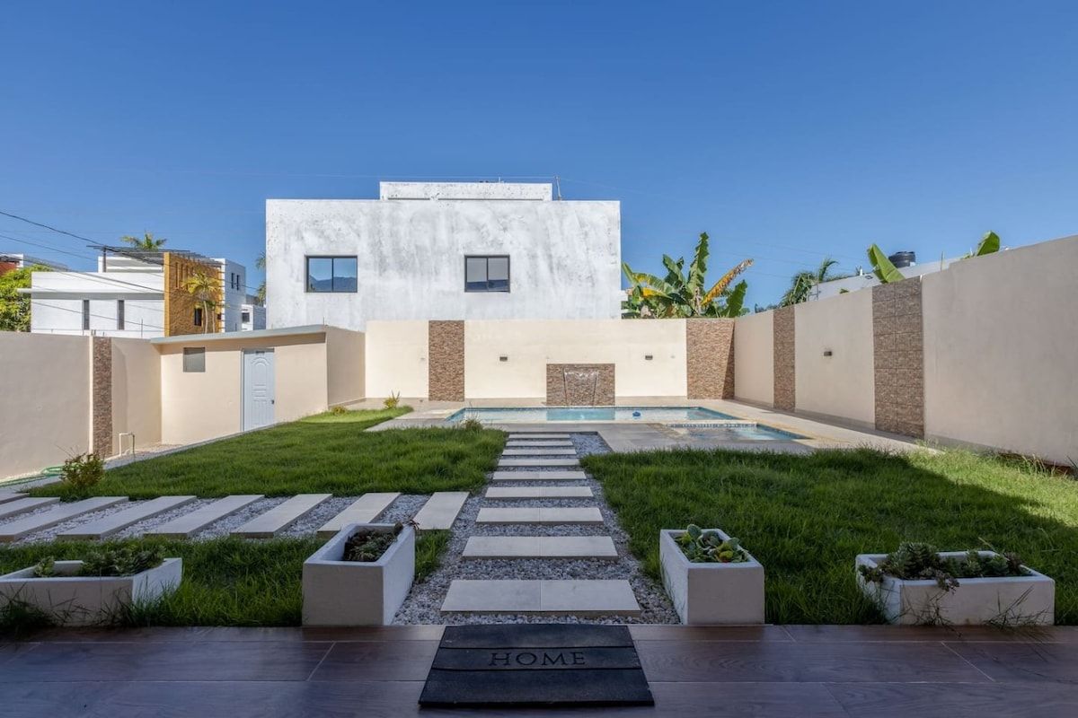 A modern house with a swimming pool, a clear sky, and a 'HOME' sign in the foreground.