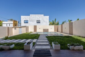 Une maison moderne avec une piscine, un ciel dégagé et un panneau indiquant « MAISON » au premier plan.
