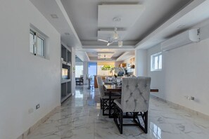 A spacious dining area with a high ceiling, modern lighting fixtures, and a marble floor. - Private Pool Retreat | 4BR | Sleeps 8 | POP (Puerto Plata)