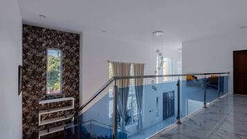 A modern interior with a marble floor, a glass railing, a stone wall, and a staircase.