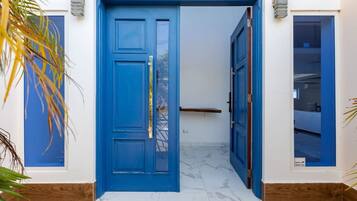 A blue door with a security panel, a wooden floor, and a white wall with a small window.