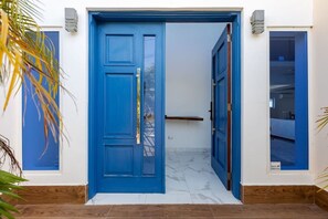 Une porte bleue dotée d’un panneau de sécurité, un plancher en bois et un mur blanc avec une petite fenêtre.