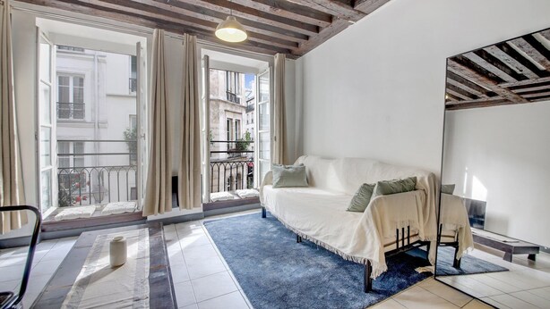 A room with a white sofa, a blue rug, and a wooden ceiling. - Paris Marais Lombards (Paris)