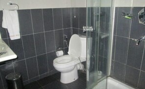 Een badkamer met toilet, douchecabine van glas en een wastafel.