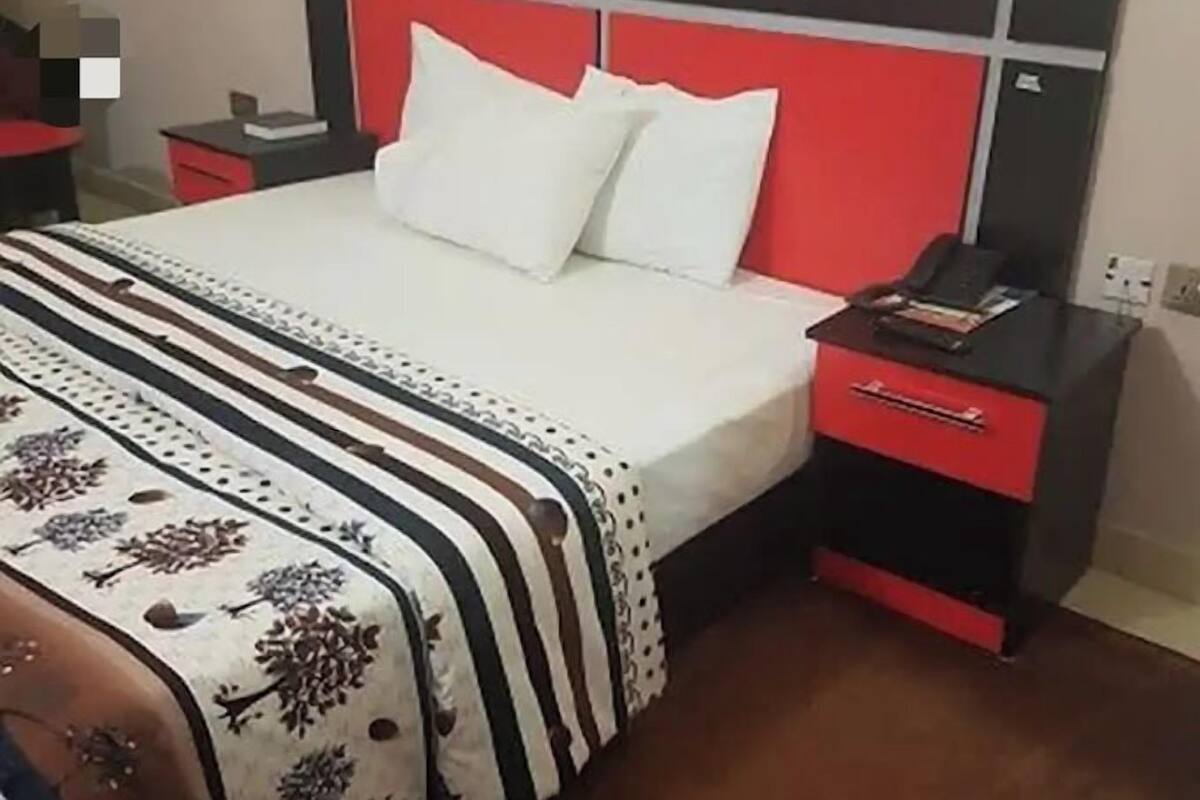 A bed with a white and black striped bedspread, a red headboard, and a bedside table with a red drawer.