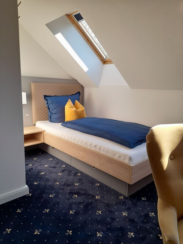 A compact bedroom with a bed, a desk, and a chair. - Gästehaus Weinberge (Elsterwerda)