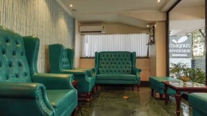 A lobby with green upholstered chairs, a marble floor, and a sign for Magnus Riverside. - Magnus Riverside Boutique Hotels (Pune)