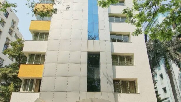 Un edificio de varios pisos con fachada blanca y una franja vertical azul.