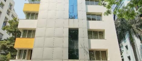 A multi-story building with a white facade and a blue vertical stripe.