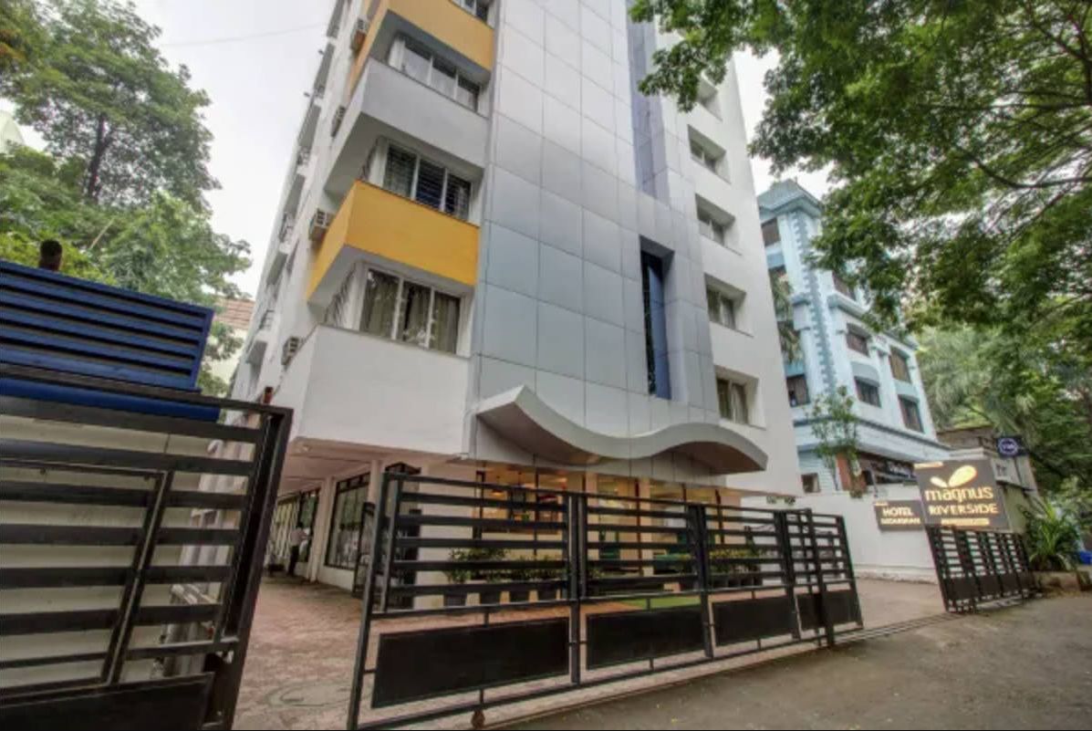 A modern hotel with a curved facade, multiple balconies, and a gated entrance.