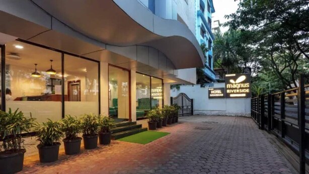 A hotel entrance with a modern design, glass doors, and a sign for 'Magnus Riverside Hotel'. - Magnus Riverside Boutique Hotels (Pune)