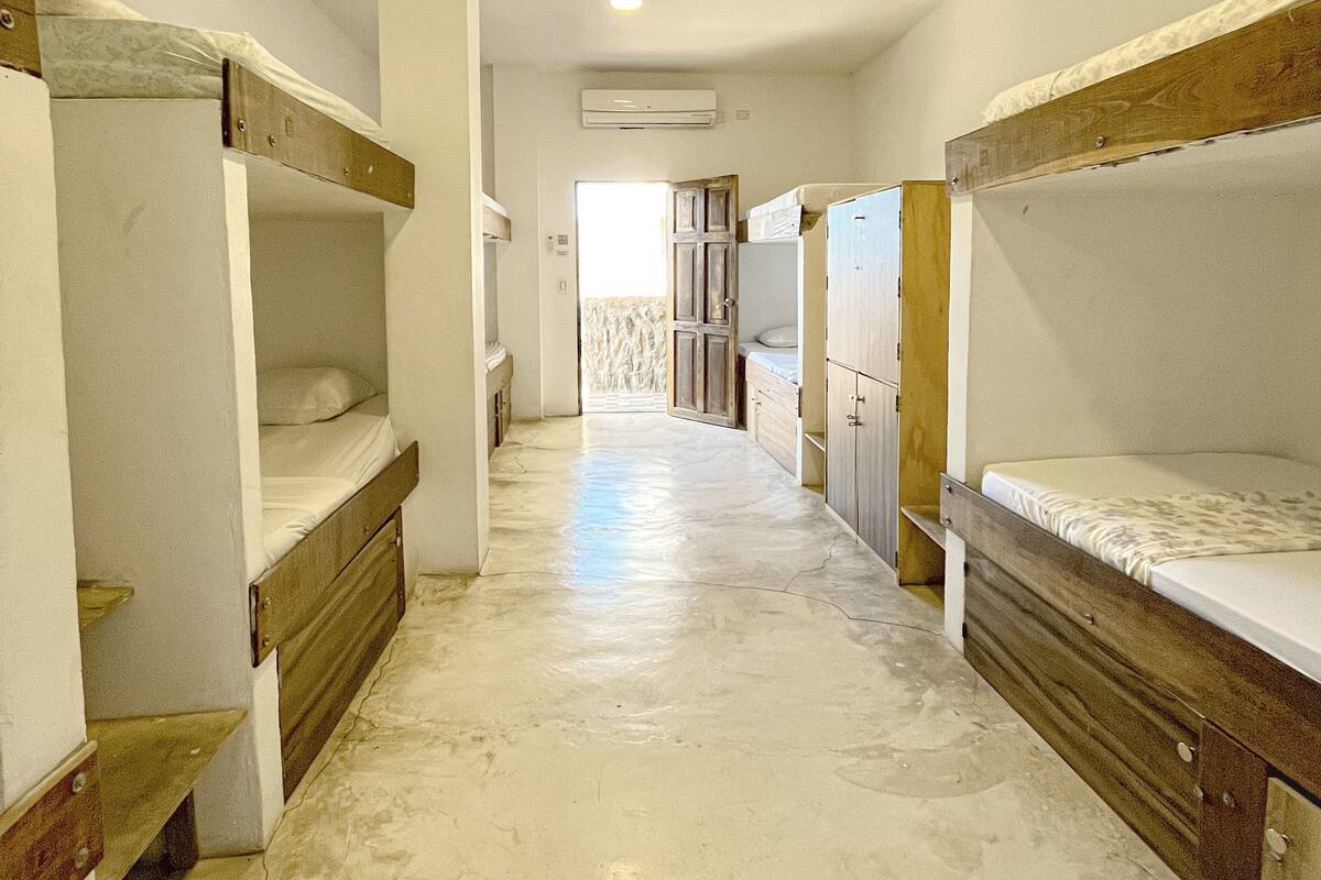 A narrow corridor with bunk beds on either side, leading to a door at the end.