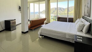 A hotel room with a bed, a small fridge, a seating area with a view, and a balcony. - HOTEL TNT MIRADOR (Santa Marta)