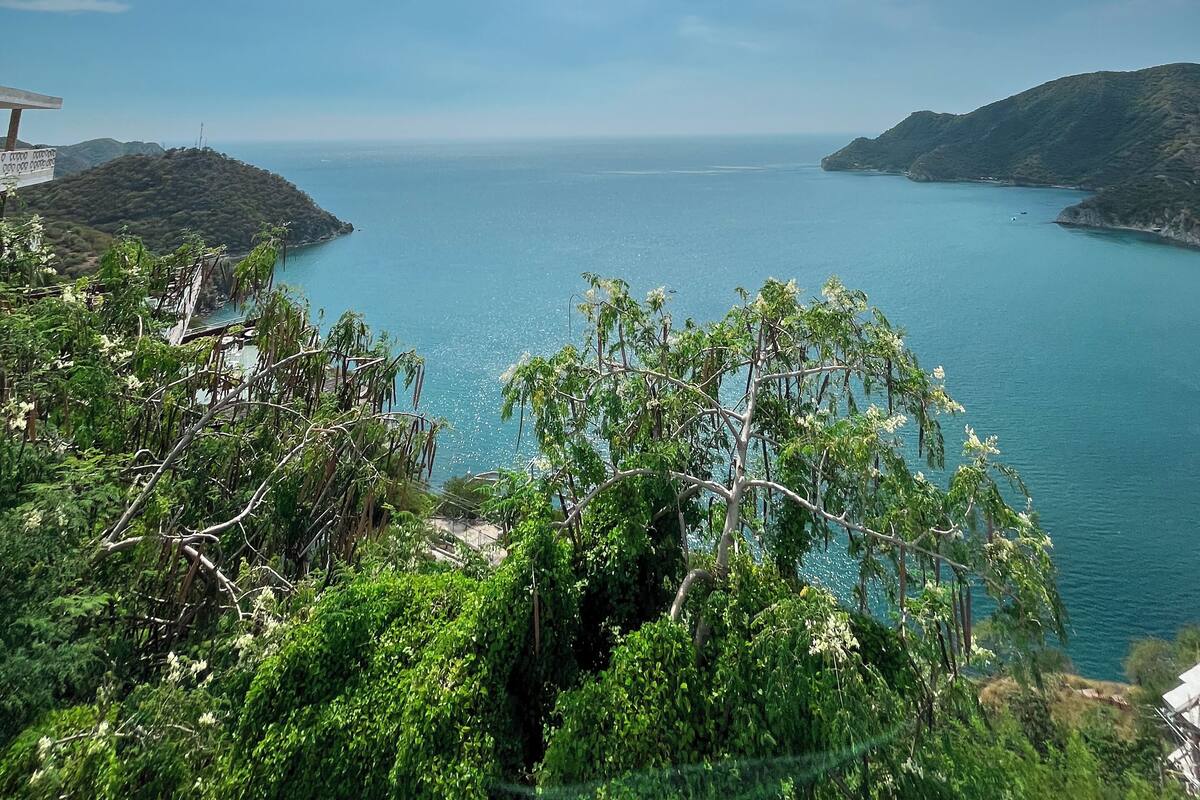 A coastal landscape with a clear sky, calm sea, and lush greenery.