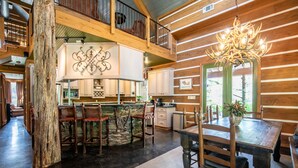 A rustic interior with a wooden dining table, chairs, a chandelier, and a stone accent wall. - The CPL, 3BR Oxford Retreat by Velvet Ditch Villas (Batesville)