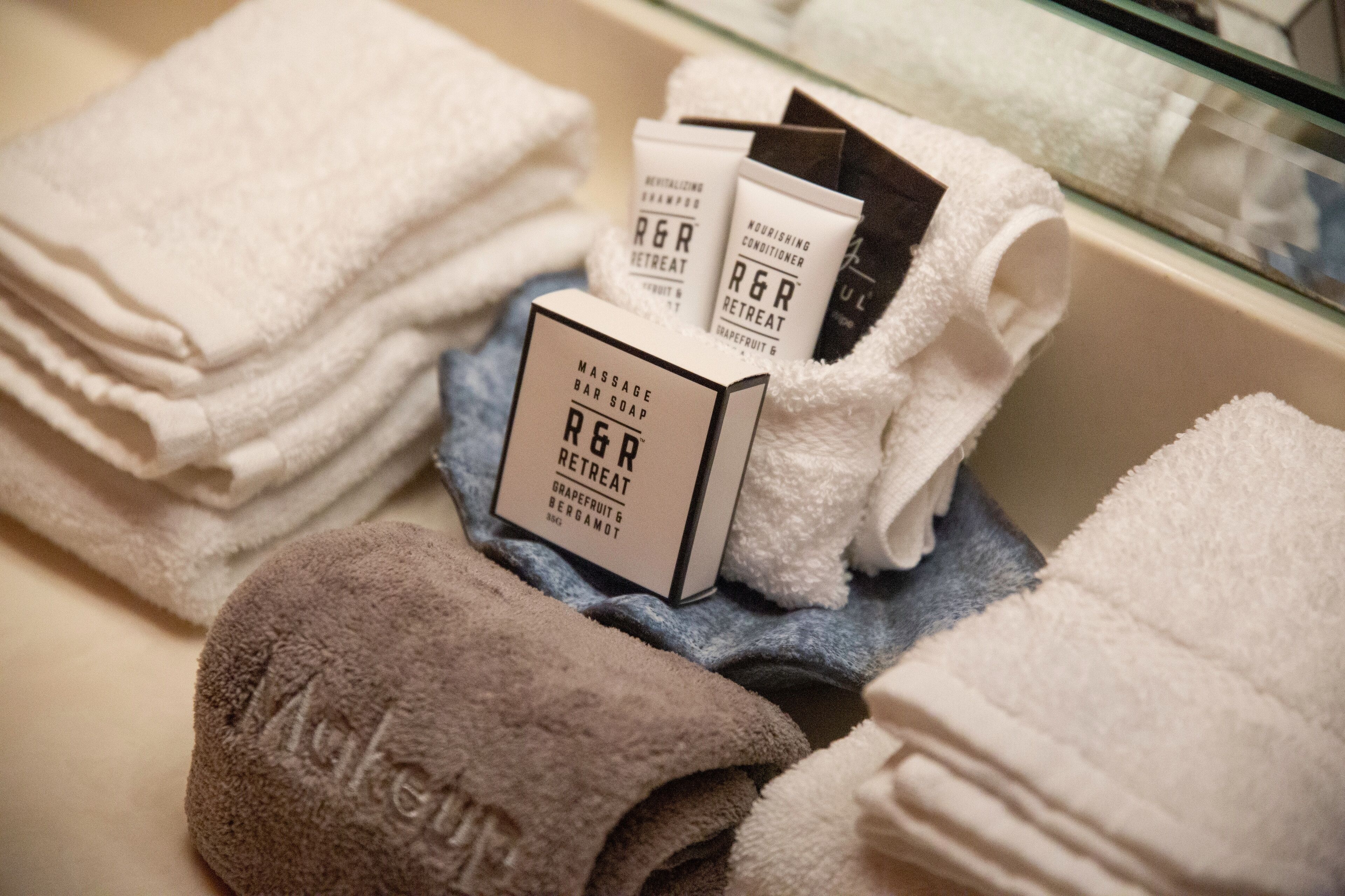 A stack of towels and a bar soap box with the brand name 'R&R Retreat'.