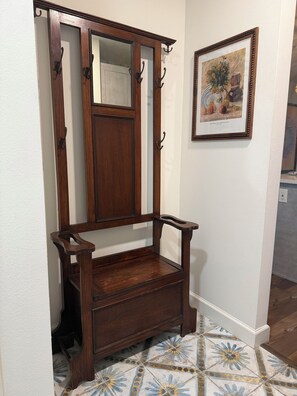 Un banc en bois avec un miroir au-dessus, un tableau encadré au mur et des carreaux de sol à motifs.