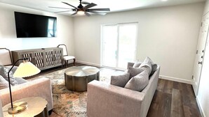 A modern living room with a sofa, coffee table, and a TV mounted on the wall.