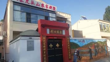 A building with a red entrance, a mural on the wall, and a satellite dish on the roof.