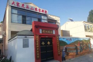Un edificio con entrada roja, un mural en la pared y una antena parabólica en el techo.
