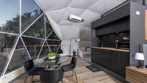 Une cuisine moderne avec un coin repas vitré, un four encastré et une grande fenêtre donnant sur un jardin.