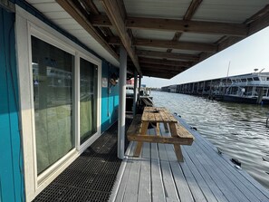 A wooden deck with a table and benches, overlooking a canal with boats. - Ana's Houseboat Located In Venice Marina SLEEPS 10 (venice)