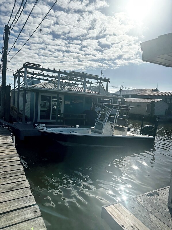 A boat docked at a wooden pier with a metal structure above it, and a building with a metal roof in the background. - Ana's Houseboat Located In Venice Marina SLEEPS 10 (venice)