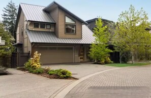 Een huis met twee verdiepingen, een garage, een oprit en een verzorgd gazon.