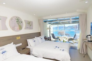 Une chambre d’hôtel avec deux lits, un bureau, une chaise et une vue sur la mer.